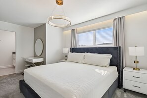 Een moderne hotelkamer met een groot bed, nachtkastjes, een spiegel en een raam met zonwering.