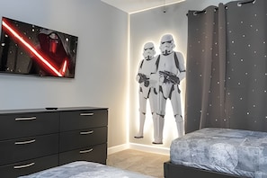 A bedroom with a Star Wars-themed wall art, a dresser, and a bed. - Villa Smile - 4bd/3ba Storey Lake Luxury Themed (Kissimmee)