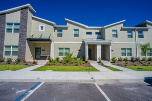A modern multi-story building with a flat roof, large windows, and a landscaped front yard. - 4BR Storey Lake Townhome, Heated Pool (Kissimmee)