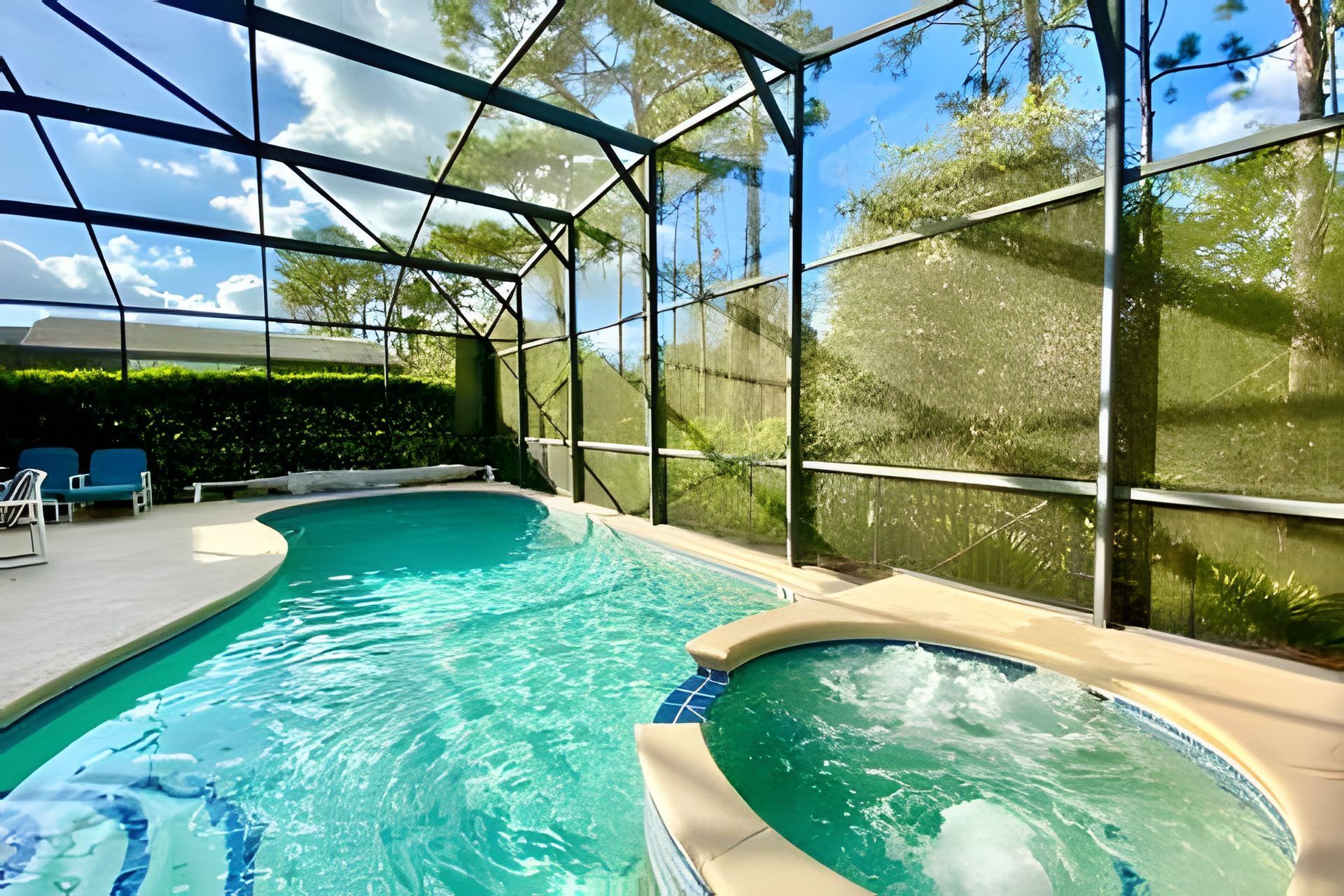 Una piscina interior con agua azul cristalina, rodeada por paredes de vidrio y una estructura de armazón metálico.
