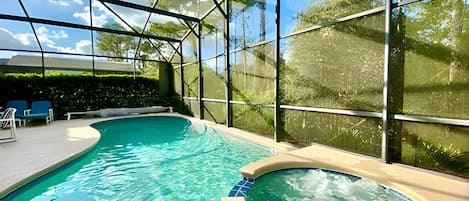 An indoor swimming pool with clear blue water, surrounded by glass walls and a metal frame structure.