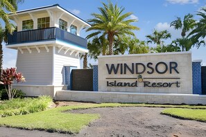 Schild für Windsor Island Resort mit einem modernen Gebäude und Palmen im Hintergrund.