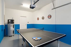 A ping pong table with paddles and balls, a projector, and a door in a room with blue and white walls. - Resort Villa With Heated Pool and Ping Pong Table (Kissimmee)