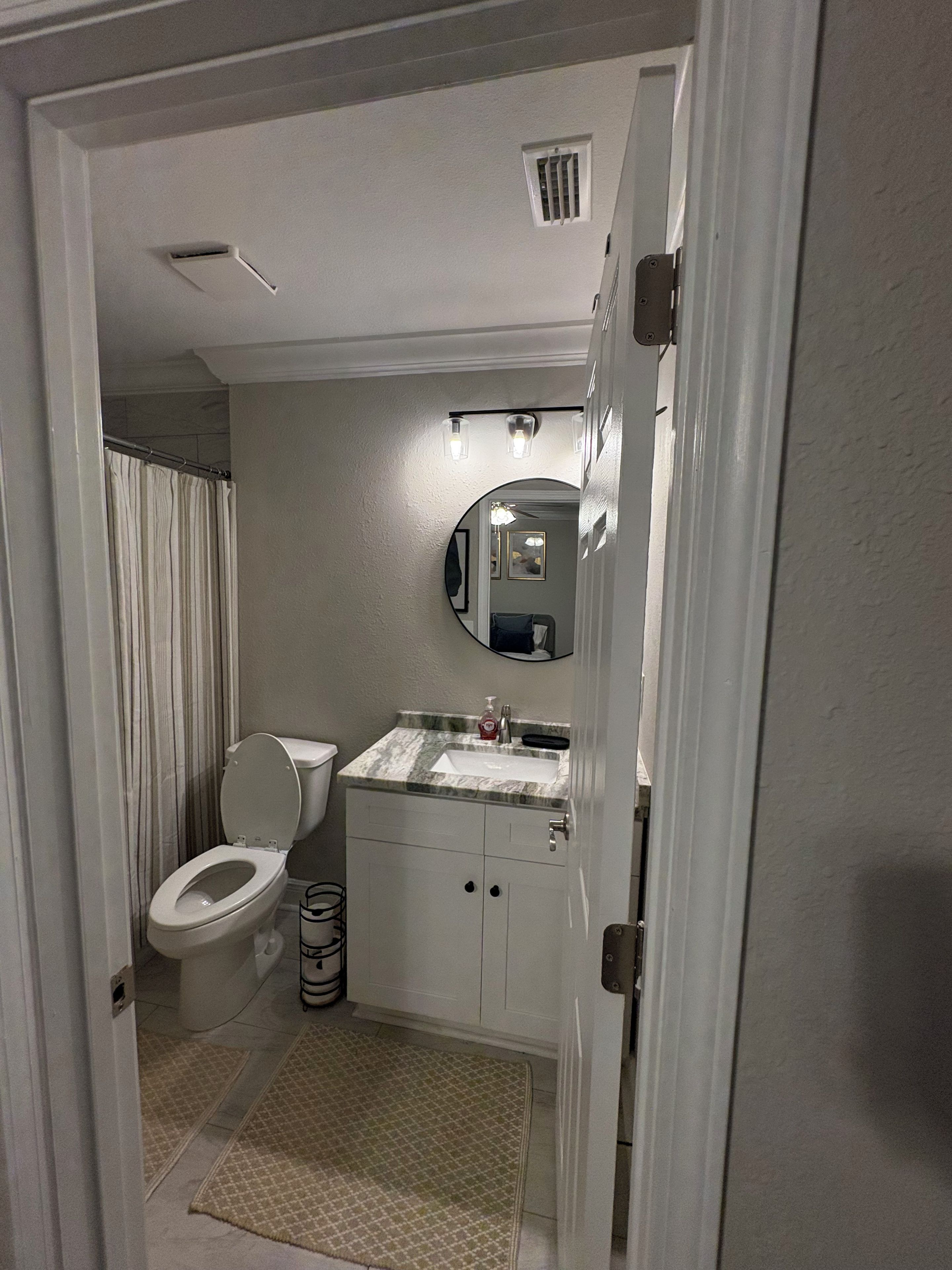 Une salle de bain équipée de toilettes, d’un lavabo, d’un miroir et d’un rideau de douche.