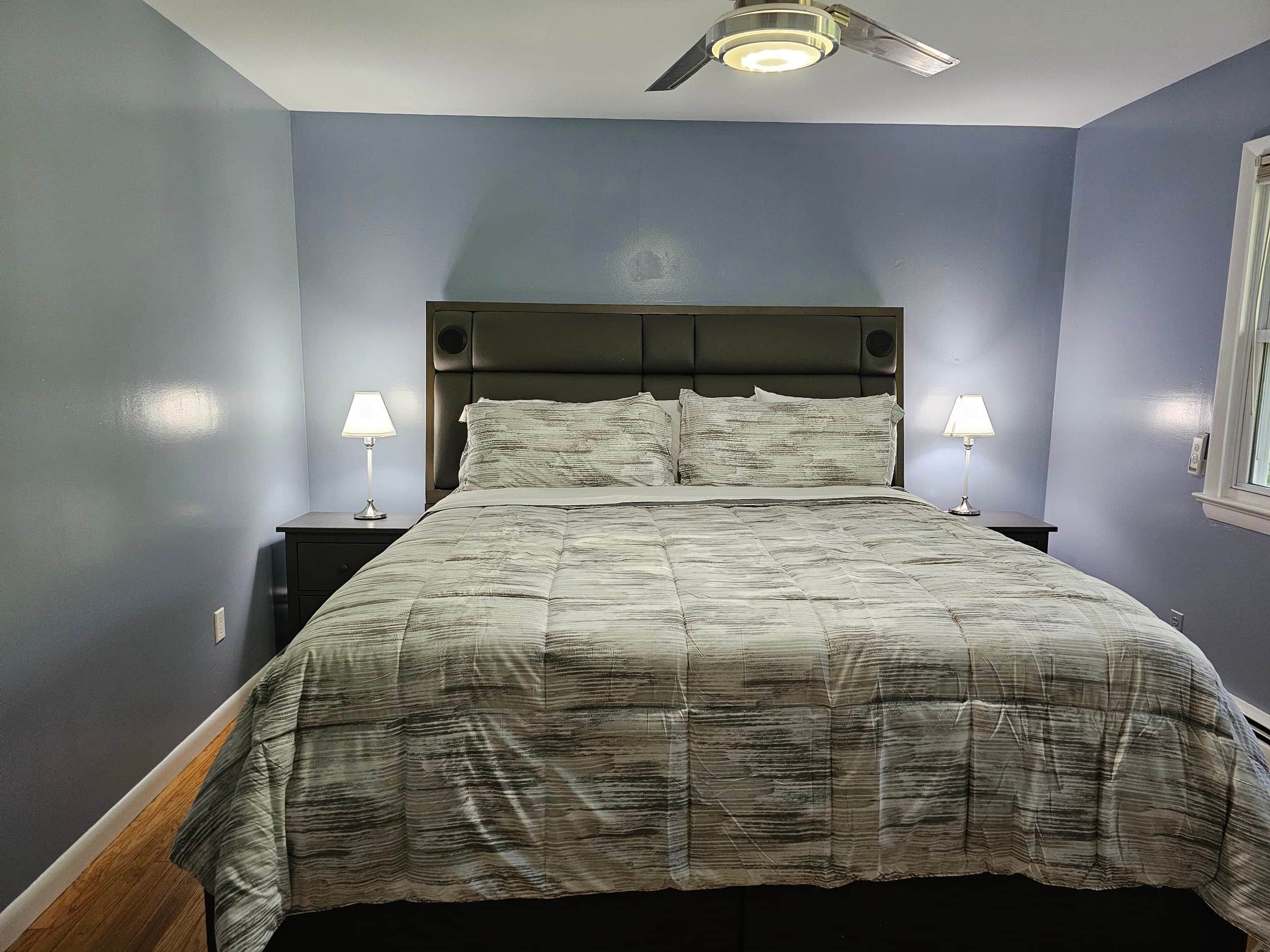 Une chambre à coucher avec un lit, deux tables de chevet et un ventilateur de plafond.
