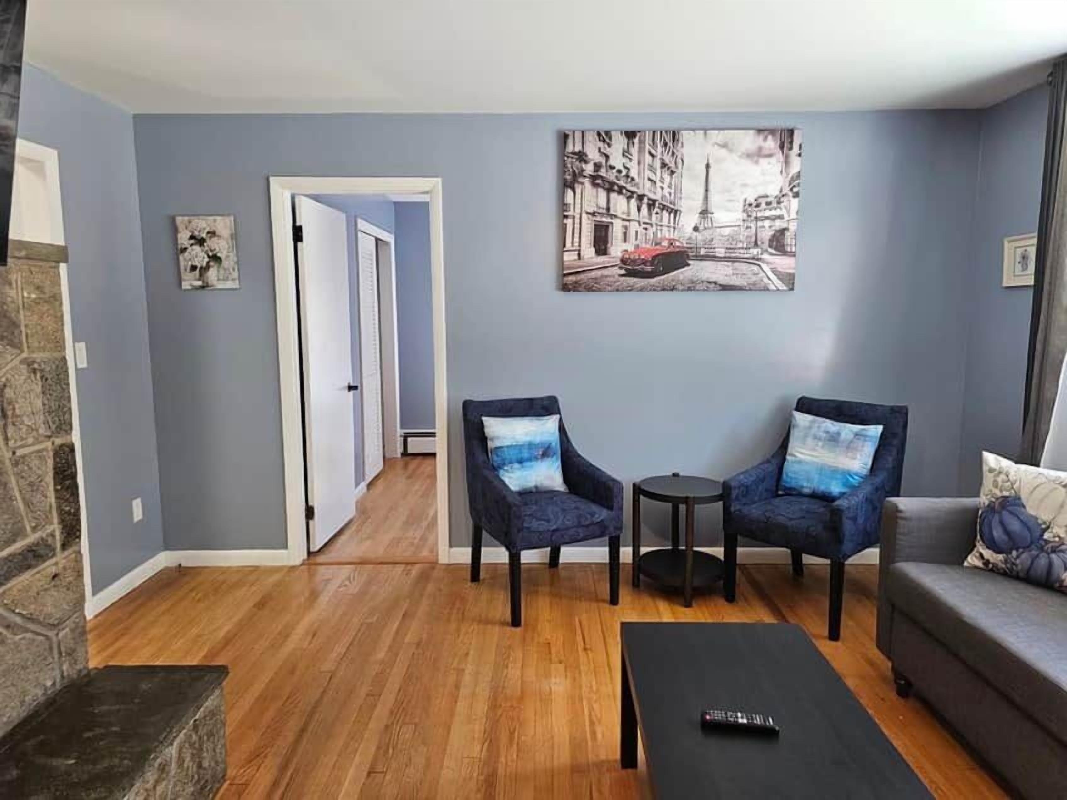 Una sala de estar con un sofá, dos sillones, una mesa de centro y un cuadro en la pared.