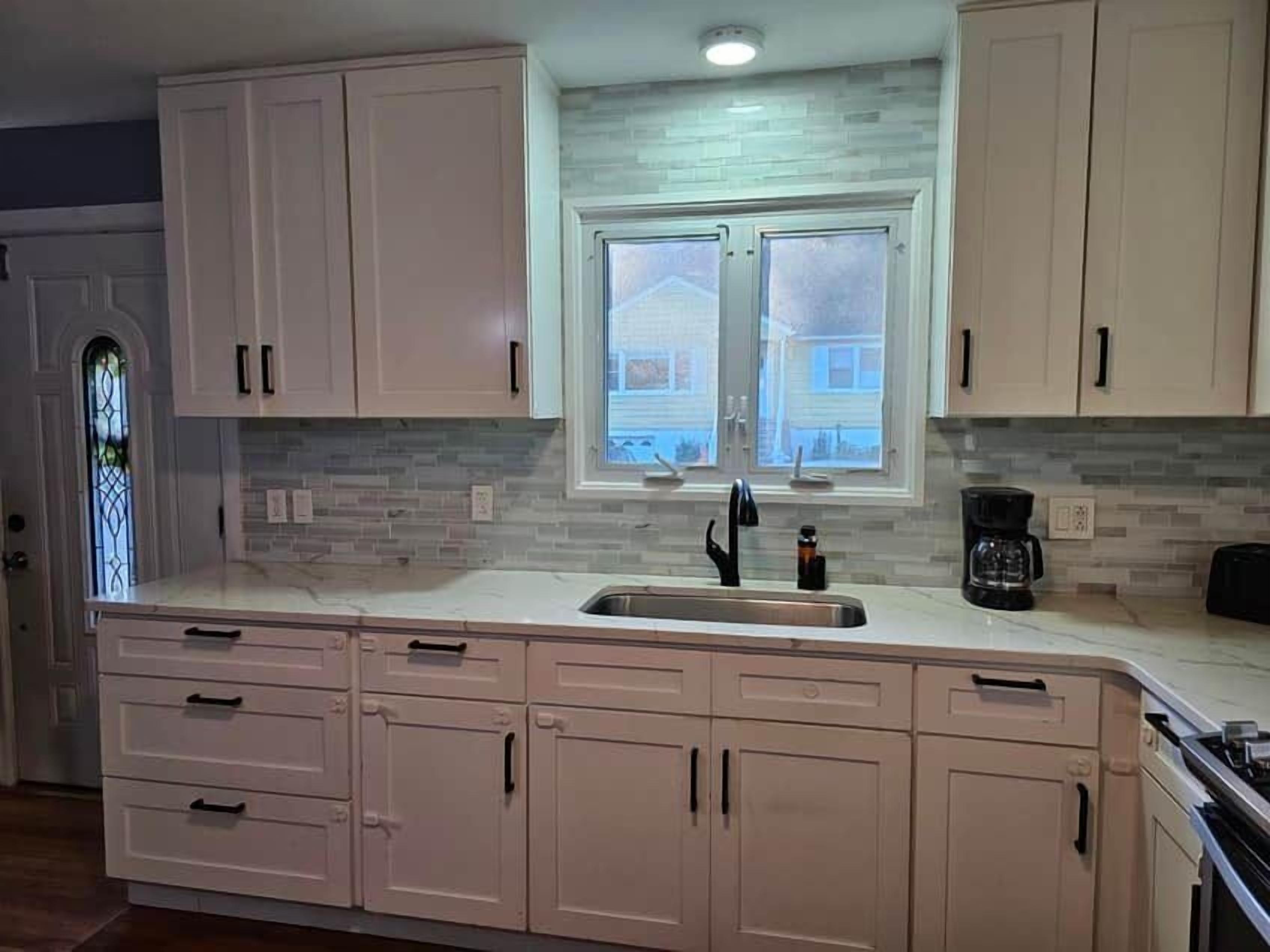 A kitchen with a window, cabinets, and a coffee maker.