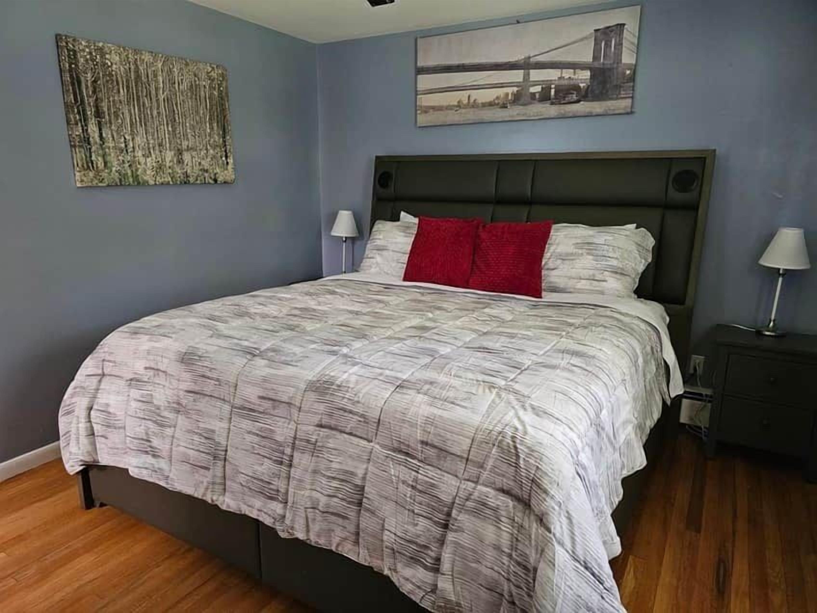 Une chambre à coucher avec un grand lit, une tête de lit, une table de chevet, une lampe et un tableau mural.