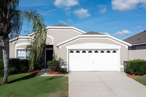 A modern two-story house with a white garage door, a covered driveway, and a well-maintained lawn. - Disney 4BR Home + Pool & Themed Bedrooms (Kissimmee)