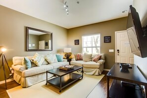 A living room with two sofas, a coffee table, a TV, and a large mirror. - 3BR West Lucaya Home With Clubhouse (Kissimmee)