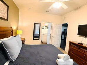 Ein Hotelzimmer mit einem Bett, einem Fernseher, einer Kommode und einem Deckenventilator.