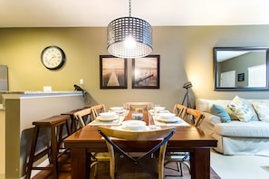 A dining area with a wooden table set for four, chairs, a clock, and framed artwork on the wall. - 3BR West Lucaya Home With Clubhouse (Kissimmee)