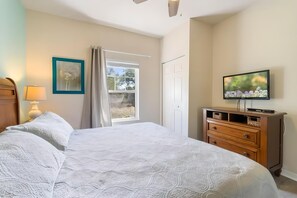 A bedroom with a bed, a dresser, a television, and a window with curtains. - 3BR Home With Resort Pool & Game Room (Kissimmee)