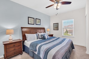 A bedroom with a bed, nightstands, a ceiling fan, and a window with blinds. - 3BR West Lucaya Home Near Disney (Kissimmee)