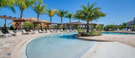 A pool area with lounge chairs and palm trees.