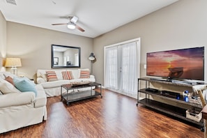 A living room with a sofa, coffee table, TV, and a ceiling fan. - Amazing 4bdr House Near Disney (Kissimmee)