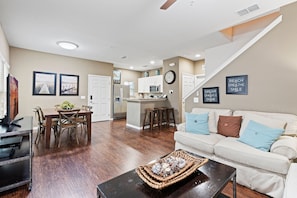 A spacious living area with a dining table, a sofa, and a kitchen in the background. - Amazing 4bdr House Near Disney (Kissimmee)