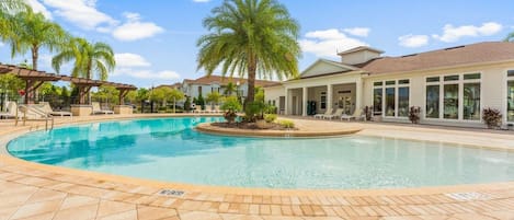 A pool area with a palm tree, lounge chairs, and a building with large windows.