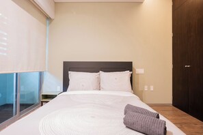 A hotel room with a bed, a nightstand, a wooden floor, and a window with blinds. - Designer 2BR in Polanco with Balcony and 24h Security (Mexico City)