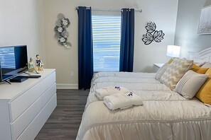 A bedroom with a bed, a dresser, a TV, and a window with curtains. - 4BR Themed Townhome in Lucaya Resort (Kissimmee)