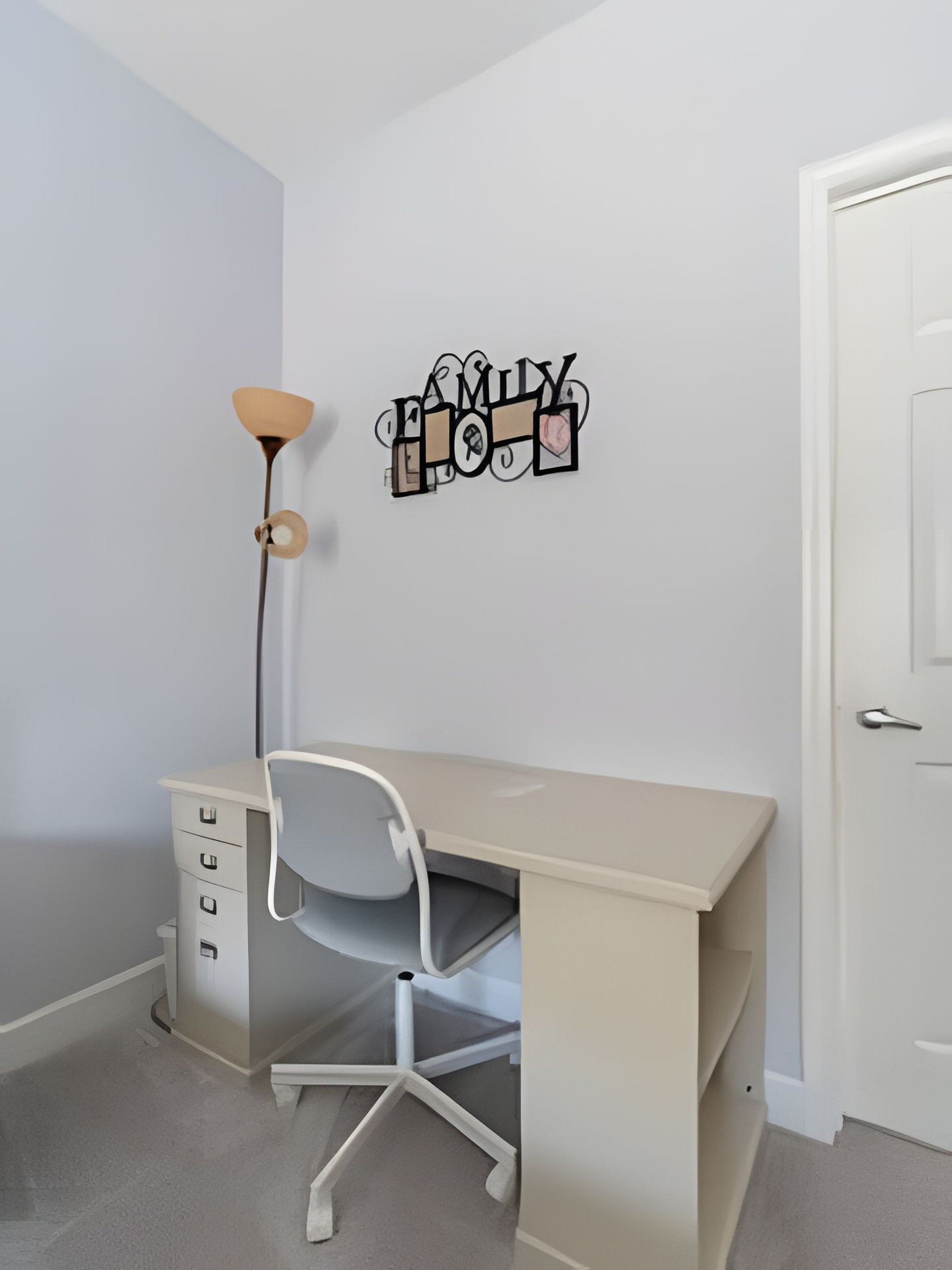 A minimalist room with a desk, chair, and a wall decoration.