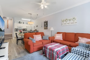 Ein modernes Wohnzimmer mit einer Sofagarnitur, einem Couchtisch und einem Essbereich im Hintergrund.