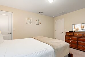 A bedroom with a bed, a dresser, and two wall-mounted paintings. - 5BR Storey Lake Home With Private Pool (Kissimmee)