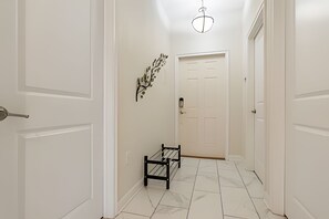 A hallway with white walls, a black bench, and a white door at the end. - 5BR Storey Lake Home With Private Pool (Kissimmee)