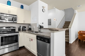 A modern kitchen with stainless steel appliances, white cabinetry, and a small island. - 4BR Lucaya Village Home, Sleeps 10 (Kissimmee)