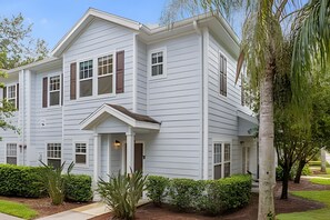 A two-story house with a front porch, multiple windows, and a well-maintained garden. - 4BR Lucaya Village Home, Sleeps 10 (Kissimmee)