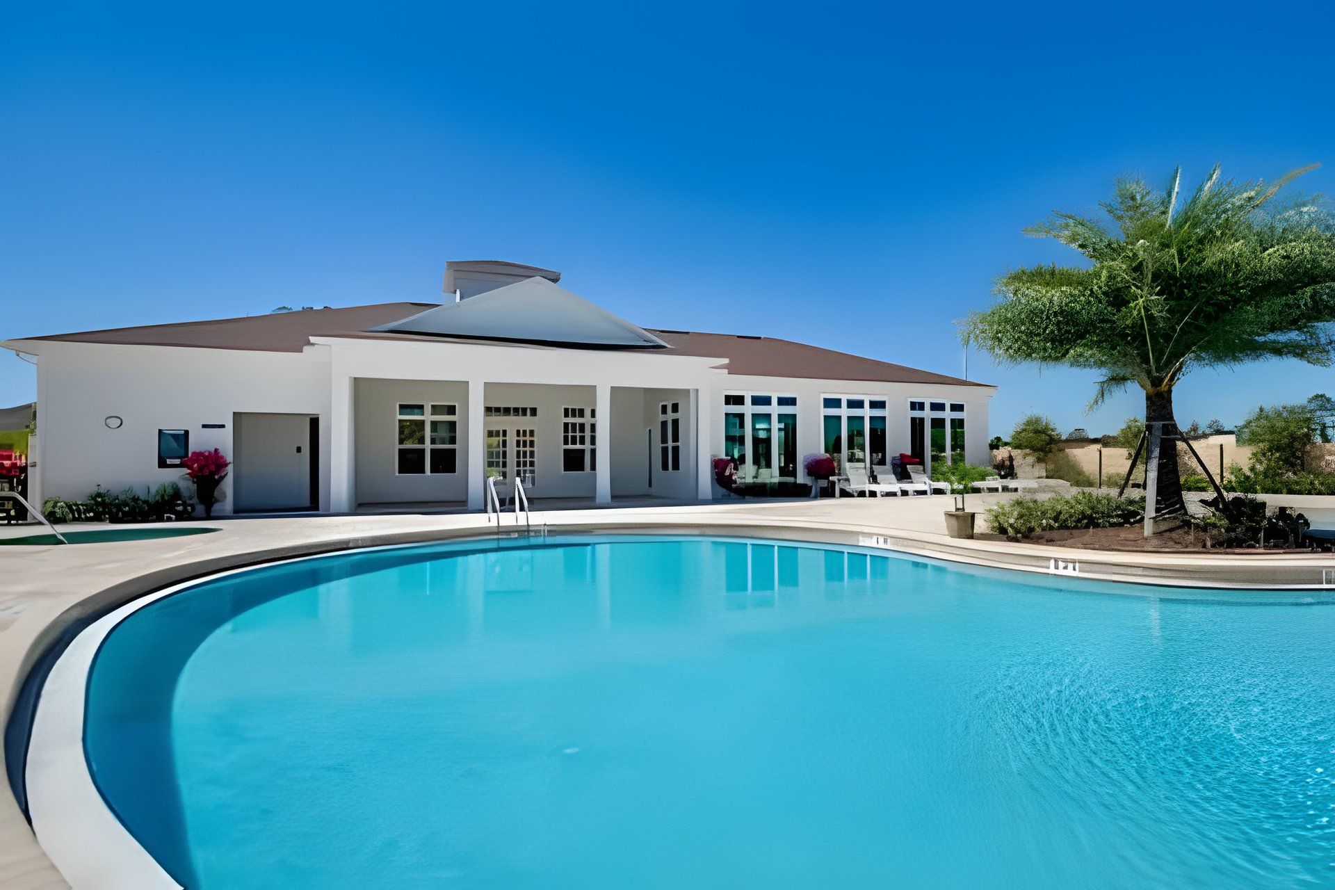 A modern building with a swimming pool, large windows, and outdoor seating.