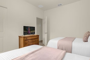 A bedroom with two beds, a wooden dresser, and a television on a stand. - 4BR Lucaya Village Home, Sleeps 10 (Kissimmee)