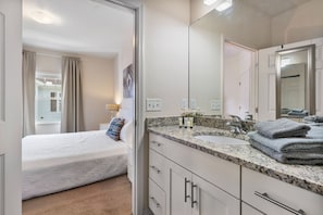 Een slaapkamer met een bed, een badkamer met een wastafel en spiegel, en uitzicht op buiten.
