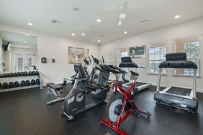 Un gimnasio con cintas de correr, bicicletas estáticas y mancuernas.