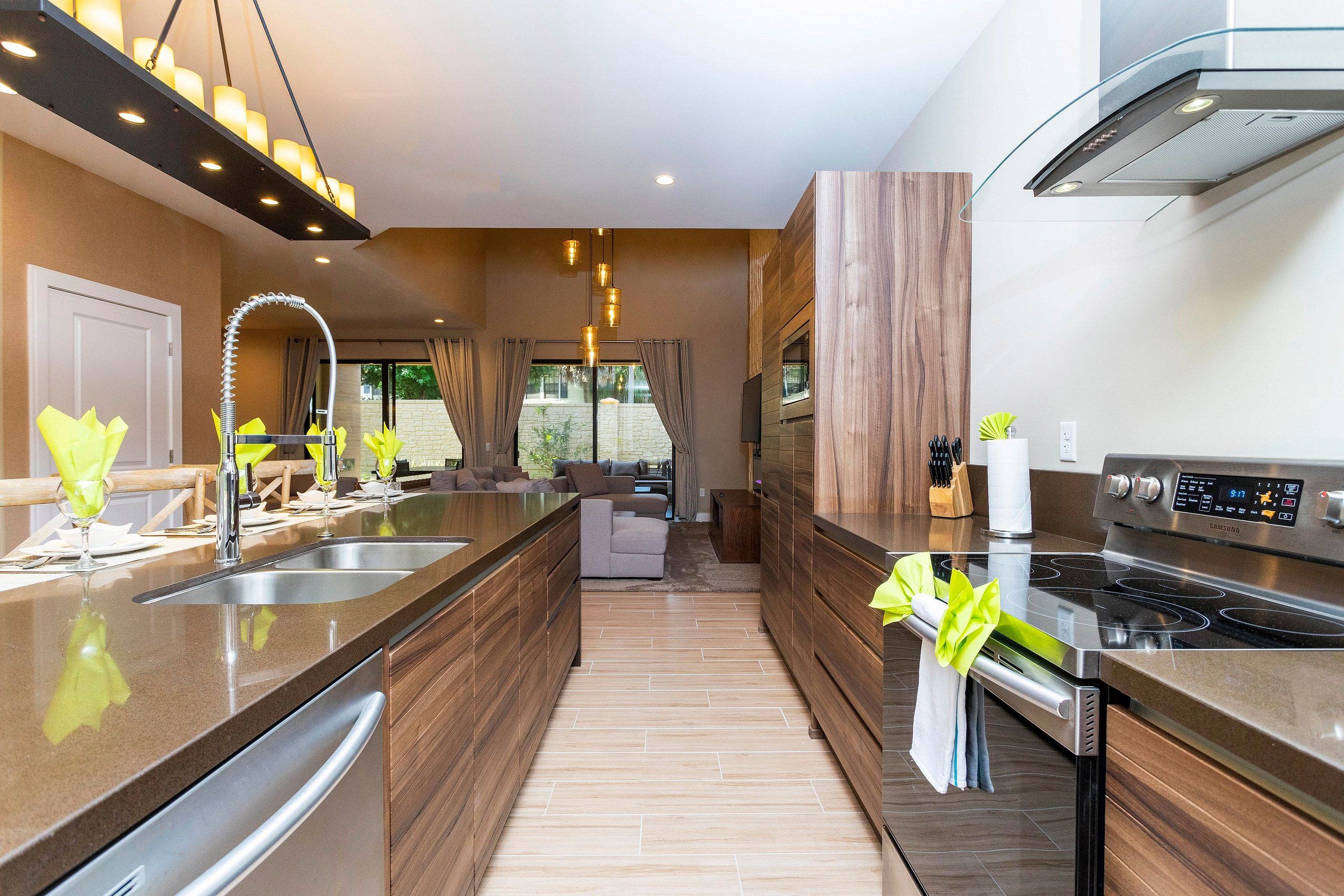 A modern kitchen with a large island, stainless steel appliances, and a view to the outside.