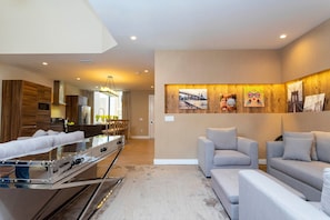 A modern living room with a sofa set, a kitchen area with a stainless steel appliance, and a dining area with a table and chairs. - 3BR Magic Village Townhome Near Disney (Kissimmee)