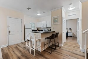 A modern kitchen with white cabinets, a black countertop, and two bar stools. - 4BR Gated Home Near Disney, Sleeps 10 (Kissimmee)