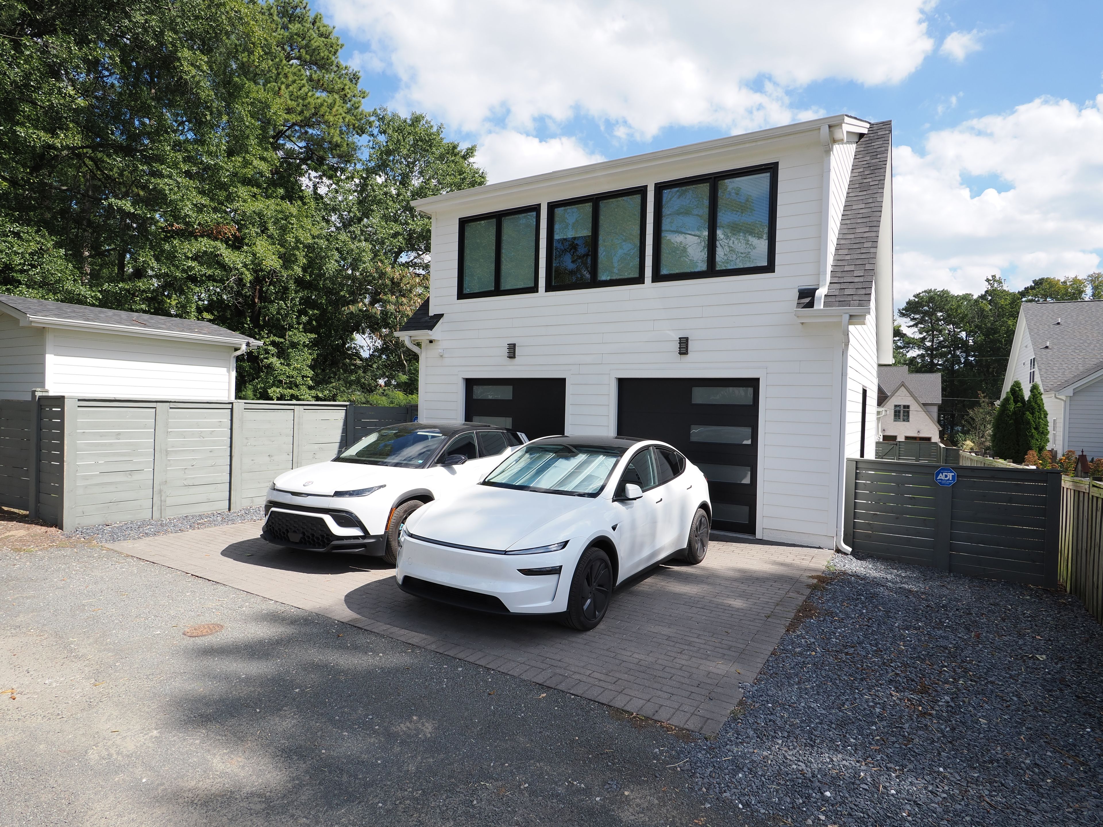 Ein modernes, zweistöckiges Haus mit Garage, zwei weiße Autos vor der Tür und einem gepflegten Einfahrt.