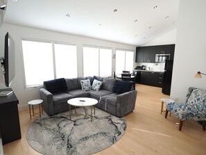 Ein modernes Wohnzimmer mit einer Eckcouch, einem Couchtisch und einem gemusterten Teppich.