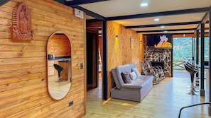 A wooden interior with a sofa, a mirror, and a fireplace.