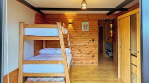 Una cabaña de madera con literas, un pasillo y una puerta que da a una habitación con un sofá.
