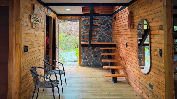 Un interior de madera con una pared de piedra, una escalera de madera y un espejo.