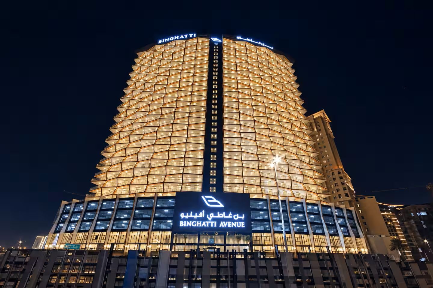 A high-rise building with a distinctive geometric facade, illuminated at night.