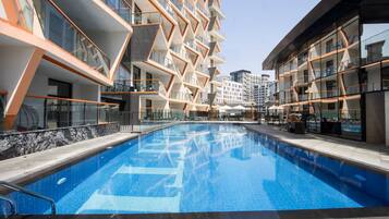 A modern hotel with a central swimming pool, multiple balconies, and a contemporary architectural design.