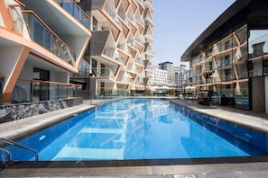 Um hotel moderno com piscina central, várias varandas e design arquitetônico contemporâneo.