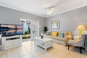 A living room with a television, a ceiling fan, a sofa with cushions, a coffee table, and a chair. - 4BR Lucaya Home w/ Disney Themes + Clubhouse (Kissimmee)