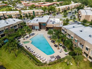 An aerial view of a hotel with a central swimming pool surrounded by lounge areas and palm trees. - Disneyarea 4BR Villa w/ BBQ Balconies & Parking (Kissimmee)