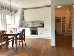 A modern kitchen with white cabinets, a wooden dining table, and chairs. - "villa Friedericia" - Apt. 04 (Wyk auf Foehr)