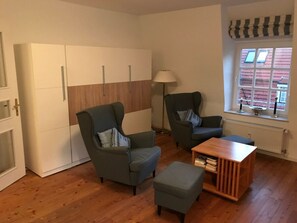 Ein Zimmer mit zwei Sesseln, einem kleinen Tisch und einem Kleiderschrank.