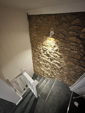 Een trap met een stenen muur en een lamp aan de muur.